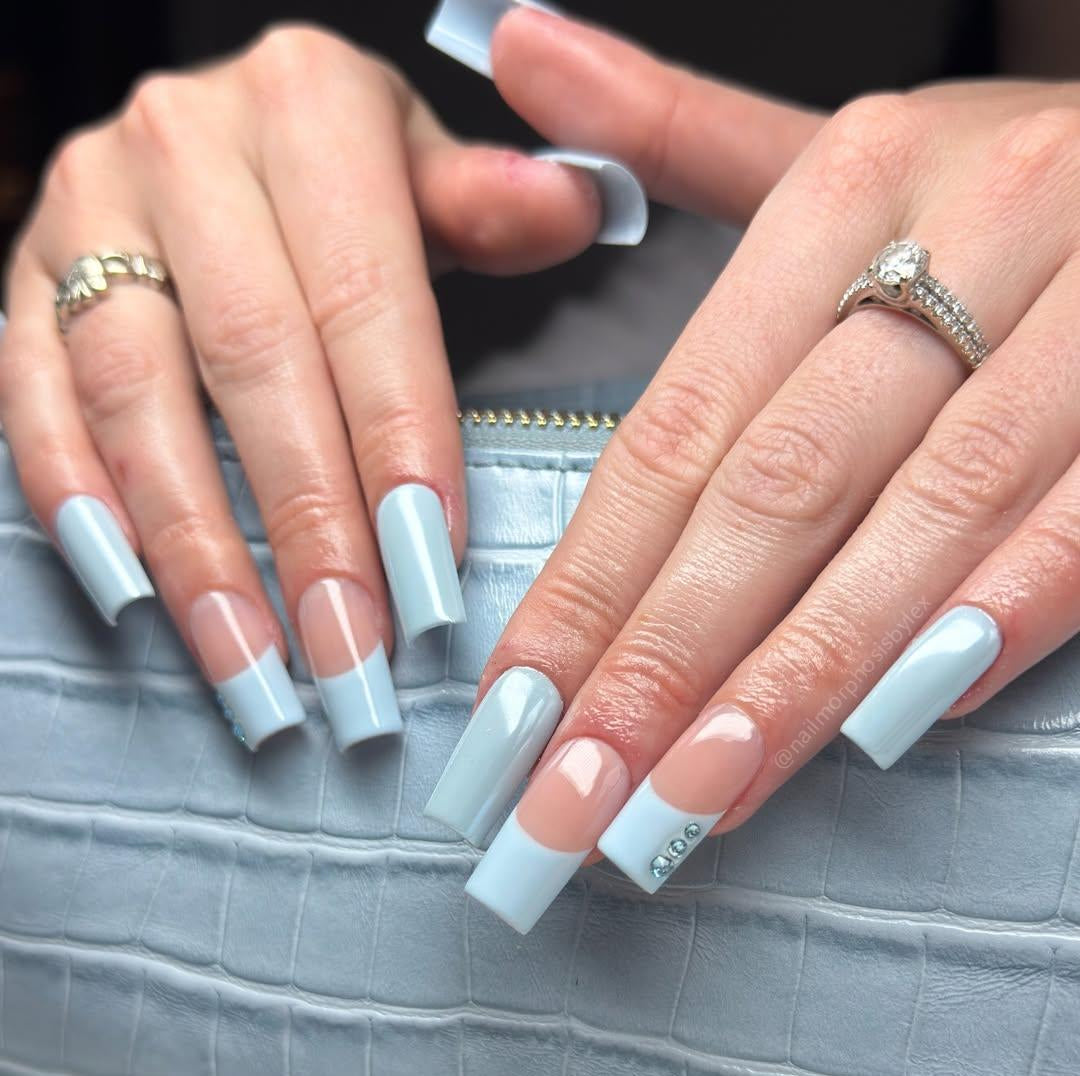 Close-up of hands with light blue nail polish on a textured gray surface